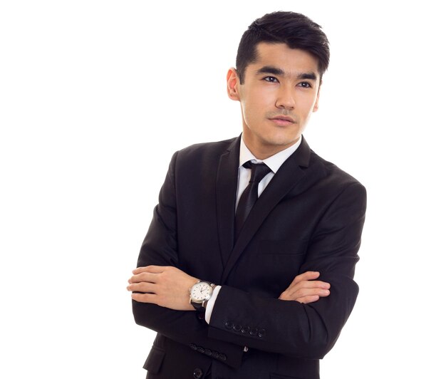 Hombre guapo con cabello negro en camisa blanca y esmoquin negro con corbata negra y reloj caro