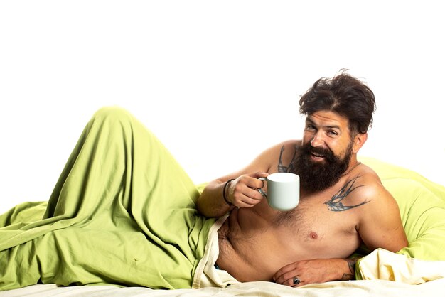 Hombre guapo en la cama sostenga la taza de té Buenos días