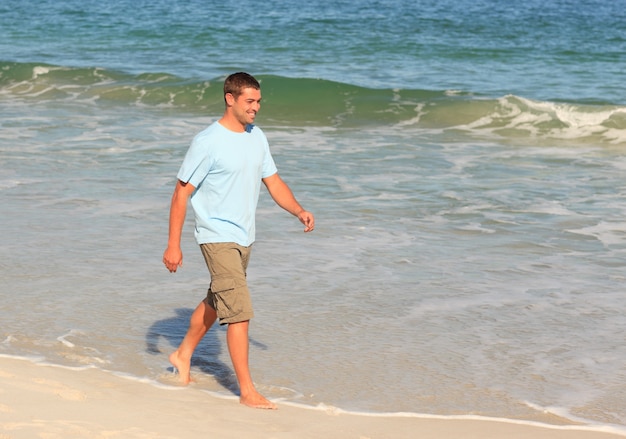 Hombre guapo caminando en la playa