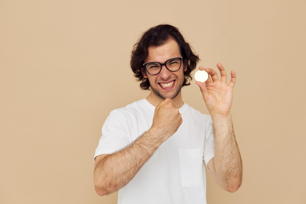 Hombre guapo en una camiseta blanca con fondo beige de criptomoneda bitcoin