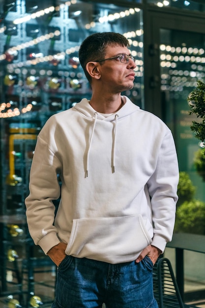 Hombre guapo con capucha blanca en la ciudad por la noche
