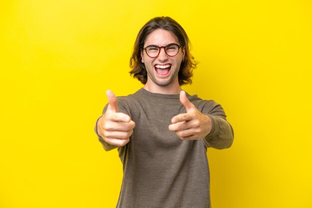 Hombre guapo caucásico aislado de fondo amarillo apuntando al frente y sonriendo