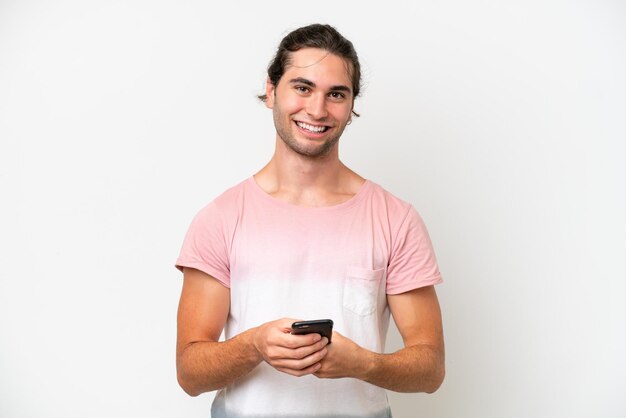 Hombre guapo caucásico aislado de fondo blanco enviando un mensaje con el móvil