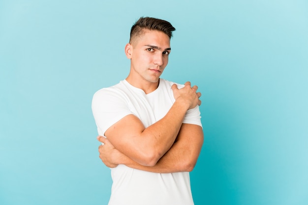 Hombre guapo caucásico joven aislado abrazos, sonriendo despreocupado y feliz.