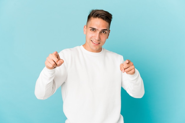 Hombre guapo caucásico joven aislado apuntando al frente con los dedos.