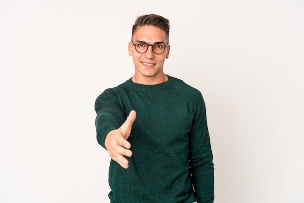 Hombre guapo caucásico joven aislado estirando la mano en gesto de saludo.