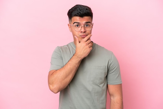 Hombre guapo caucásico joven aislado en el pensamiento de fondo rosa