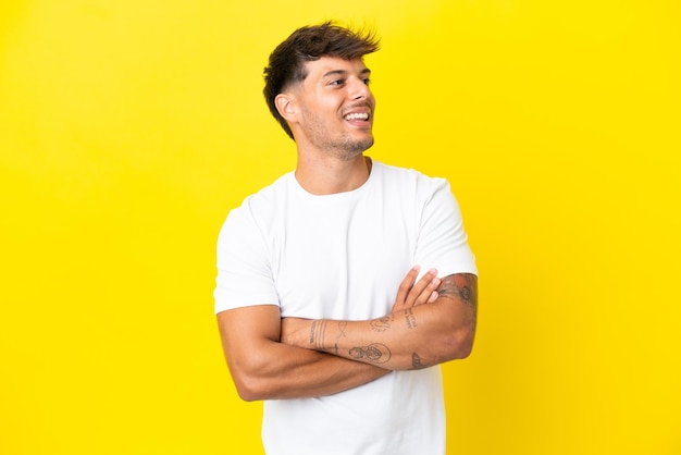 Hombre guapo caucásico joven aislado sobre fondo amarillo feliz y sonriente