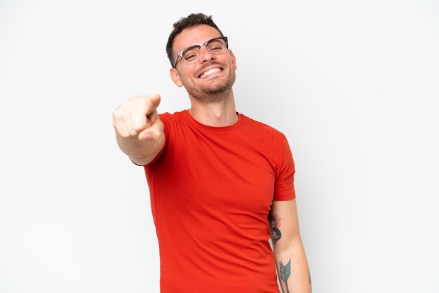 Hombre guapo caucásico joven aislado sobre fondo blanco apuntando al frente con expresión feliz