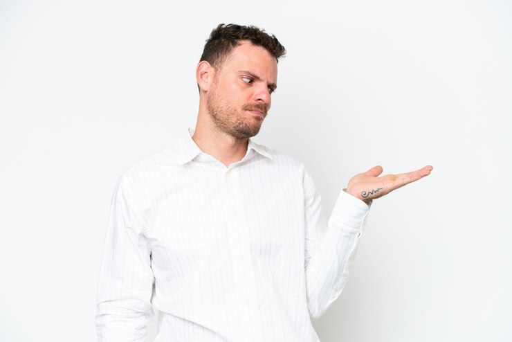 Foto hombre guapo caucásico joven aislado sobre fondo blanco sosteniendo copyspace con dudas