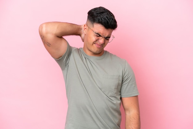 Hombre guapo caucásico joven aislado sobre fondo rosa con dolor de cuello