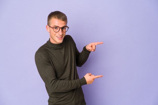 Hombre guapo caucásico joven emocionado señalando con los dedos índices de distancia.