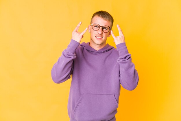 Hombre guapo caucásico joven que muestra un gesto de cuernos como un concepto de revolución.