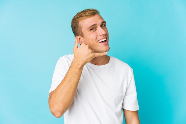 Hombre guapo caucásico joven que muestra un gesto de llamada de teléfono móvil con los dedos.