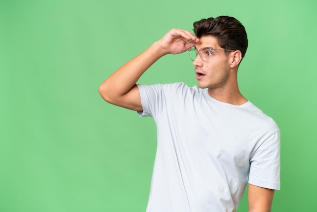 Hombre guapo caucásico joven sobre fondo aislado con expresión de sorpresa mientras mira de lado