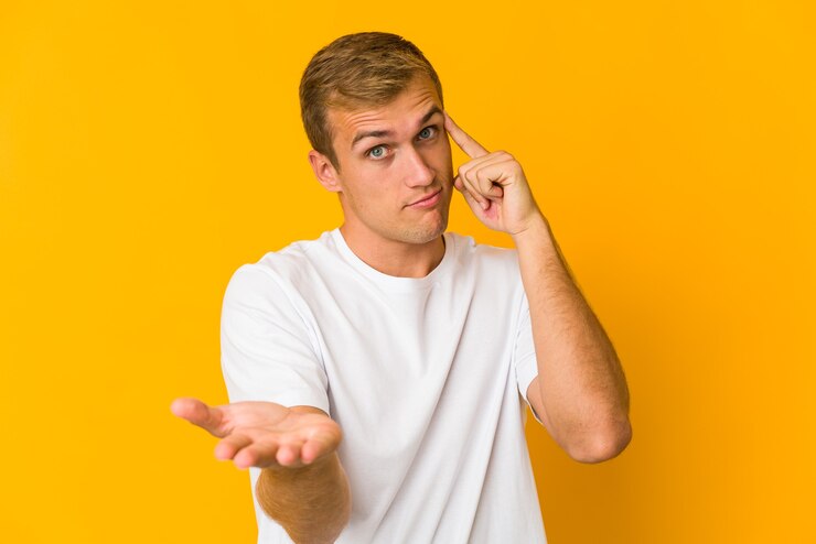 Foto hombre guapo caucásico joven sosteniendo y mostrando un producto en la mano.