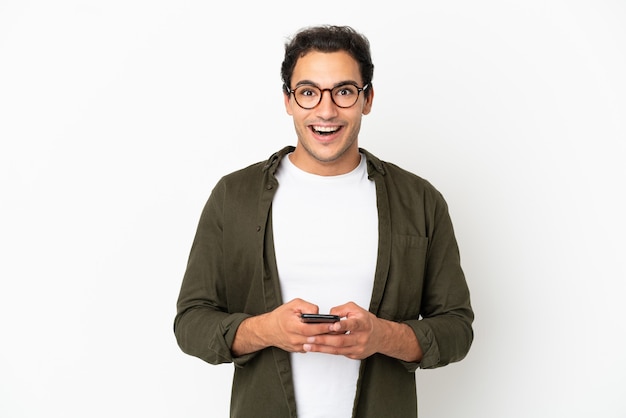 Hombre guapo caucásico sobre fondo blanco aislado sorprendido y enviando un mensaje