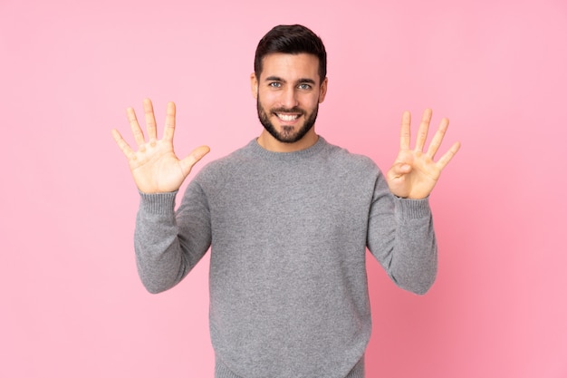 Hombre guapo caucásico sobre pared contando nueve con los dedos