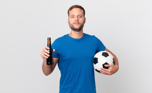 Hombre guapo con una cerveza y una pelota de fútbol