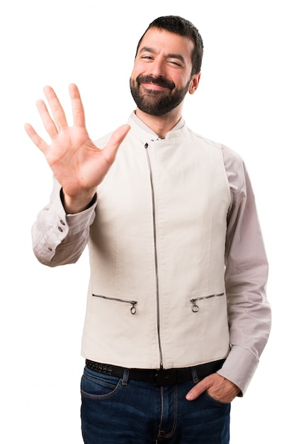 Foto hombre guapo con chaleco contando cinco en fondo blanco aislado