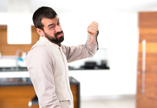 Foto hombre guapo con chaleco haciendo mala señal dentro de la casa