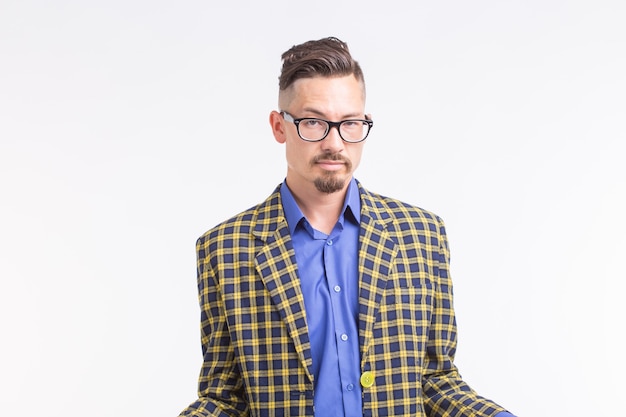 Hombre guapo en chaqueta con barba y bigote en gafas de pie sobre fondo blanco.