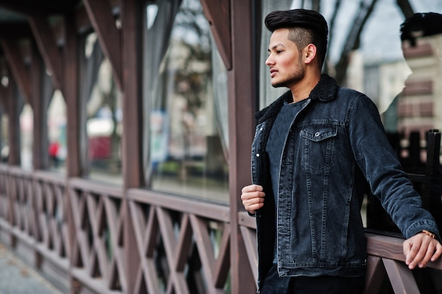 Hombre guapo en chaqueta de jeans negro planteó al aire libre