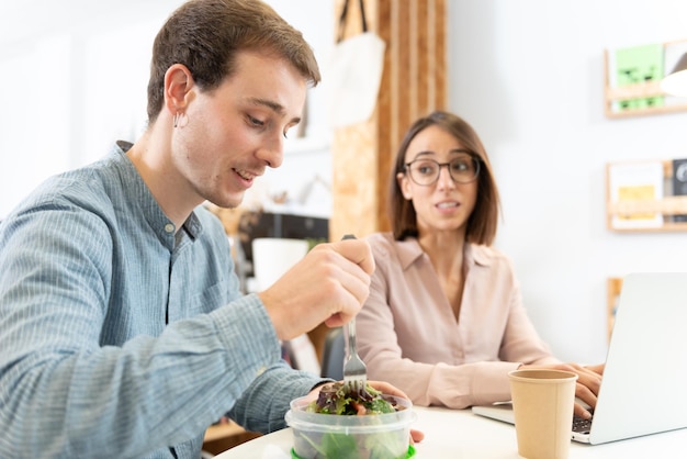 Un hombre guapo charlando con un compañero de trabajo mientras come una ensalada Concepto de hábitos de nutrición saludables