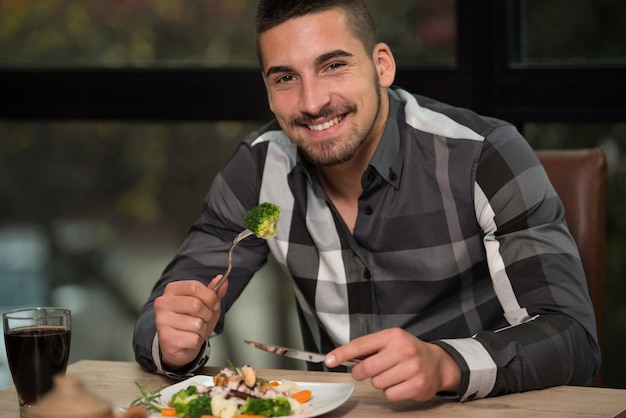 Hombre guapo comiendo en un restaurante y luciendo feliz