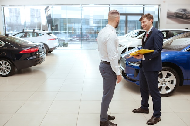 Foto hombre guapo comprar auto nuevo en el concesionario