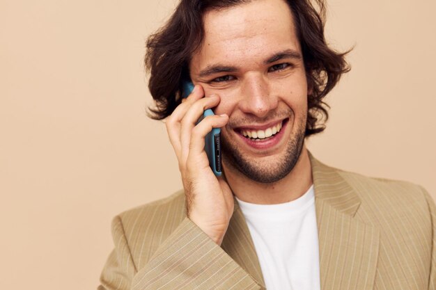 Hombre guapo comunicación por teléfono traje beige estilo elegante fondo aislado