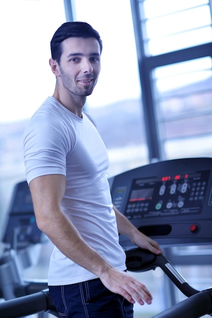 Hombre guapo corriendo en la caminadora en el gimnasio moderno