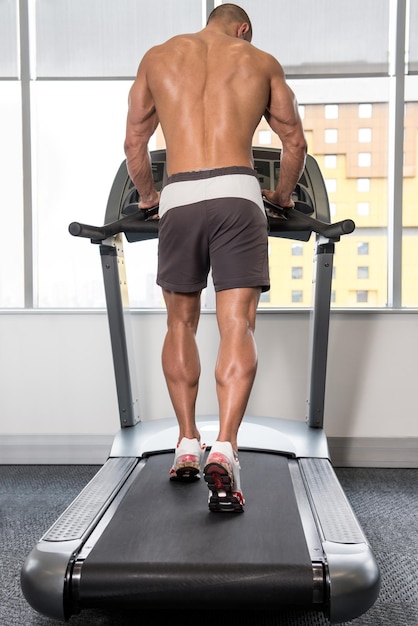 Hombre guapo corriendo en la caminadora en el gimnasio