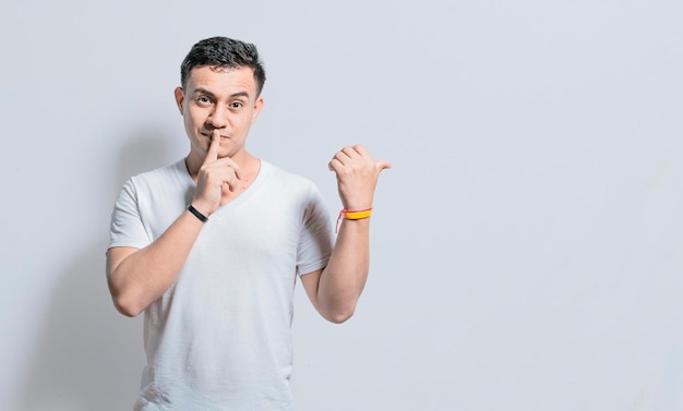 Hombre guapo con el dedo en el labio apuntando hacia un lado en un fondo aislado persona apuntando hacia un lado dando una oferta personas aisladas con el dedo en el labio apuntando hacia un lado