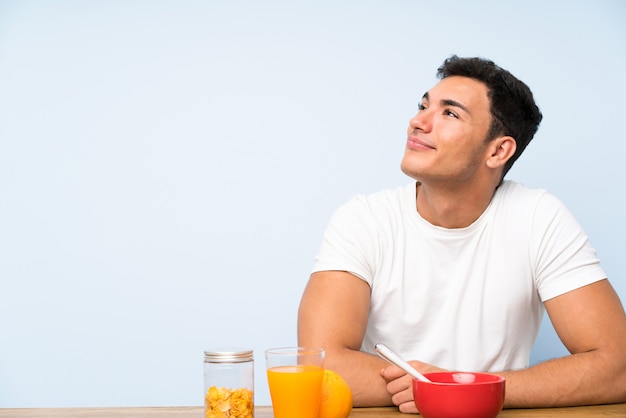 Hombre guapo en desayunar riendo y mirando hacia arriba