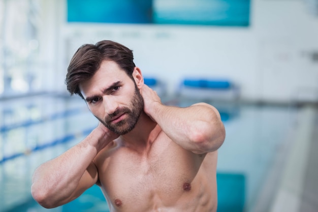 Hombre guapo con dolor de cuello en la piscina