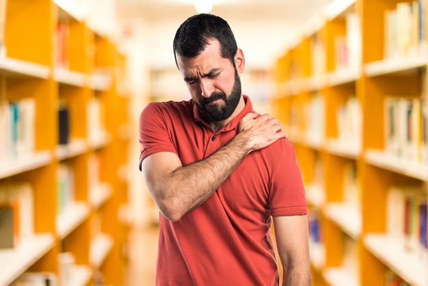 Hombre guapo con dolor de hombro sobre fondo desenfocado