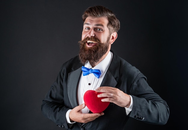 Hombre guapo en esmoquin con amor regalo de corazón para el día de san valentín san valentín