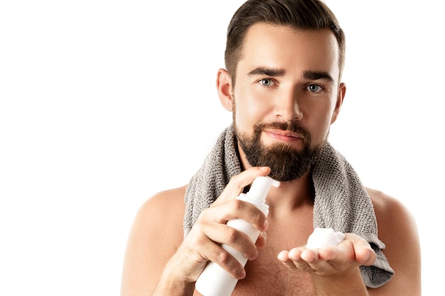 Hombre guapo con una espuma limpiadora o de afeitar sobre fondo blanco.