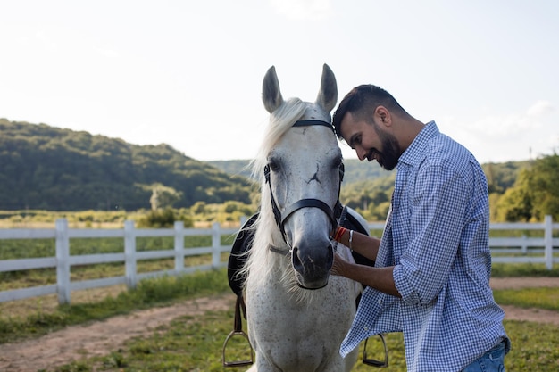 El hombre guapo está mirando a los ojos de un caballo.