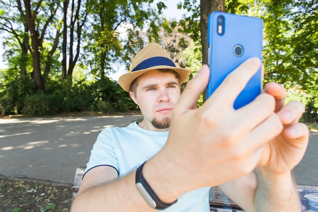 Hombre guapo está tomando un selfie al aire libre - gente caucásica - naturaleza, gente, estilo de vida y concepto de tecnología.