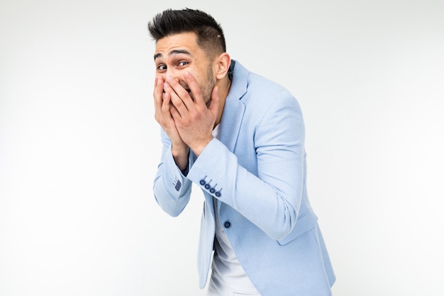 Hombre guapo en estilo clásico se ríe cubriendo su rostro con la mano