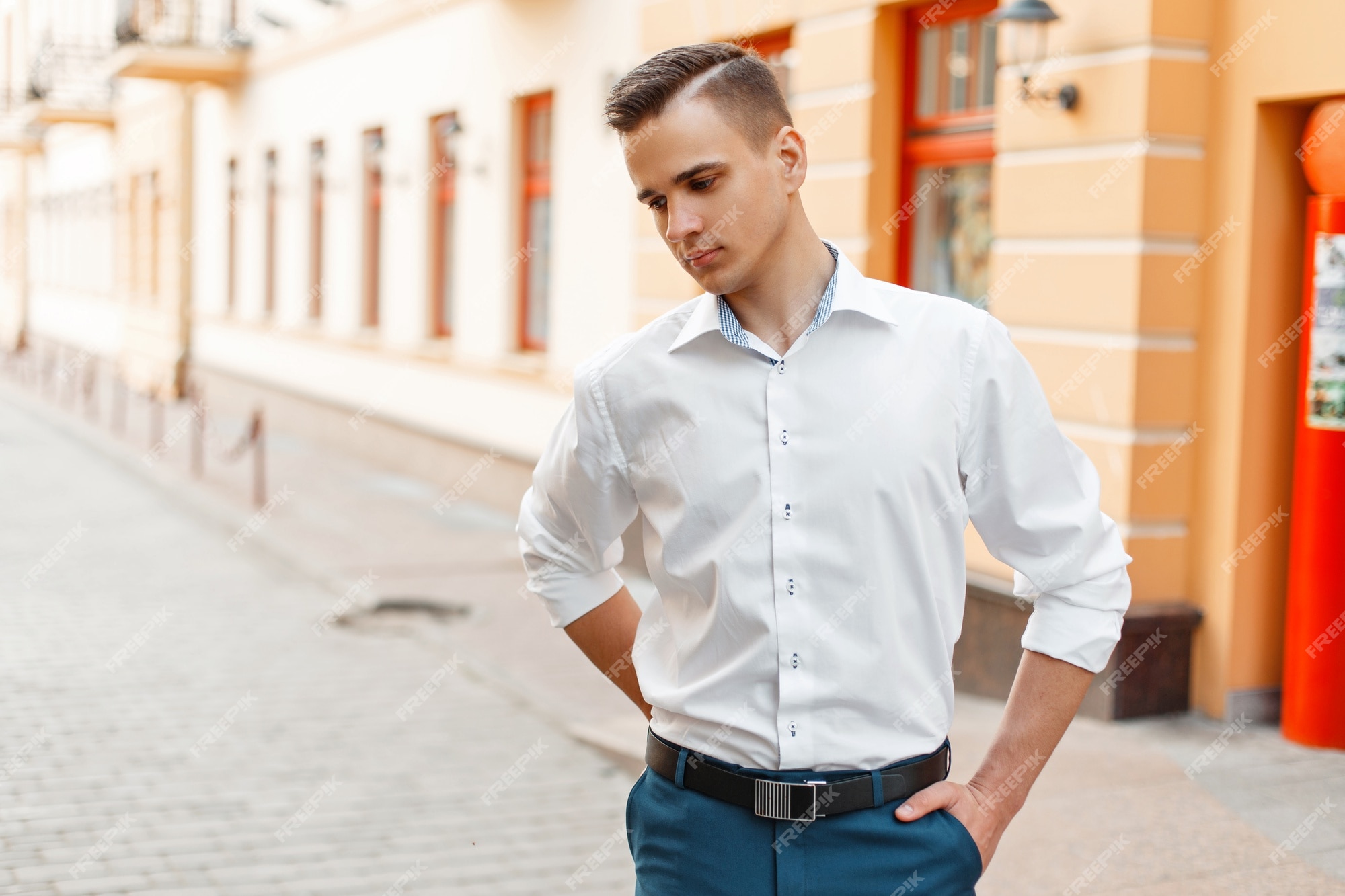 Hombre guapo con en una elegante camisa blanca y pantalón azul la ciudad | Foto Premium