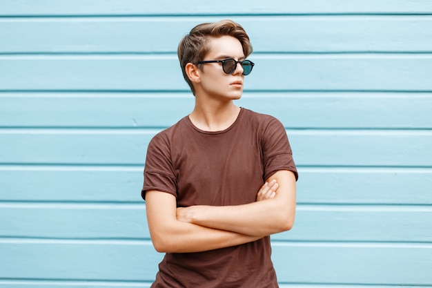 Hombre guapo con estilo joven está posando junto a una pared azul brillante.