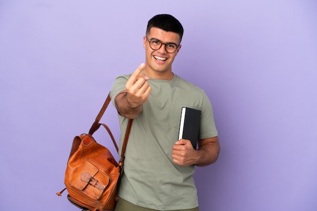 Hombre guapo estudiante sobre fondo aislado haciendo gesto de venida