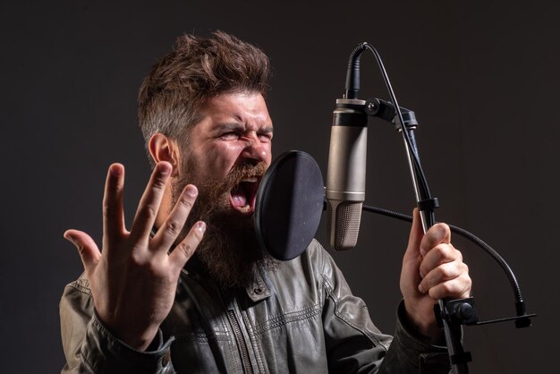 Hombre guapo en estudio de grabación interpretación musical cantante vocal cantando canción con un micrófono