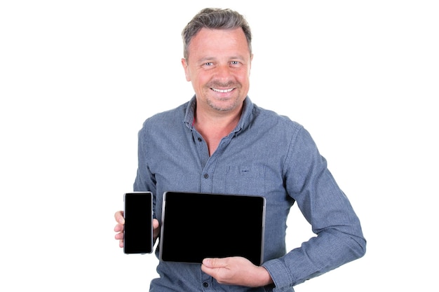 Hombre guapo feliz en ropa formal con sonrisa sostiene tableta digital y teléfono inteligente y muestra copyspace de pantalla en blanco