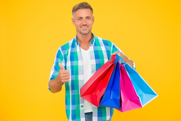 Hombre guapo feliz sosteniendo paquetes con compra preparándose para comprar regalos navideños