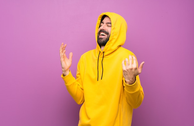 Hombre guapo feliz con sudadera amarilla