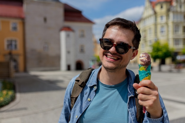 Hombre guapo con gafas de sol con helado divertirse en la ciudad